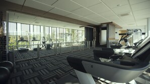 A gym with treadmills, exercise equipment, and a large windowed area with a view of the outdoors. - Emerald Palace Hotel (Naypyidaw)