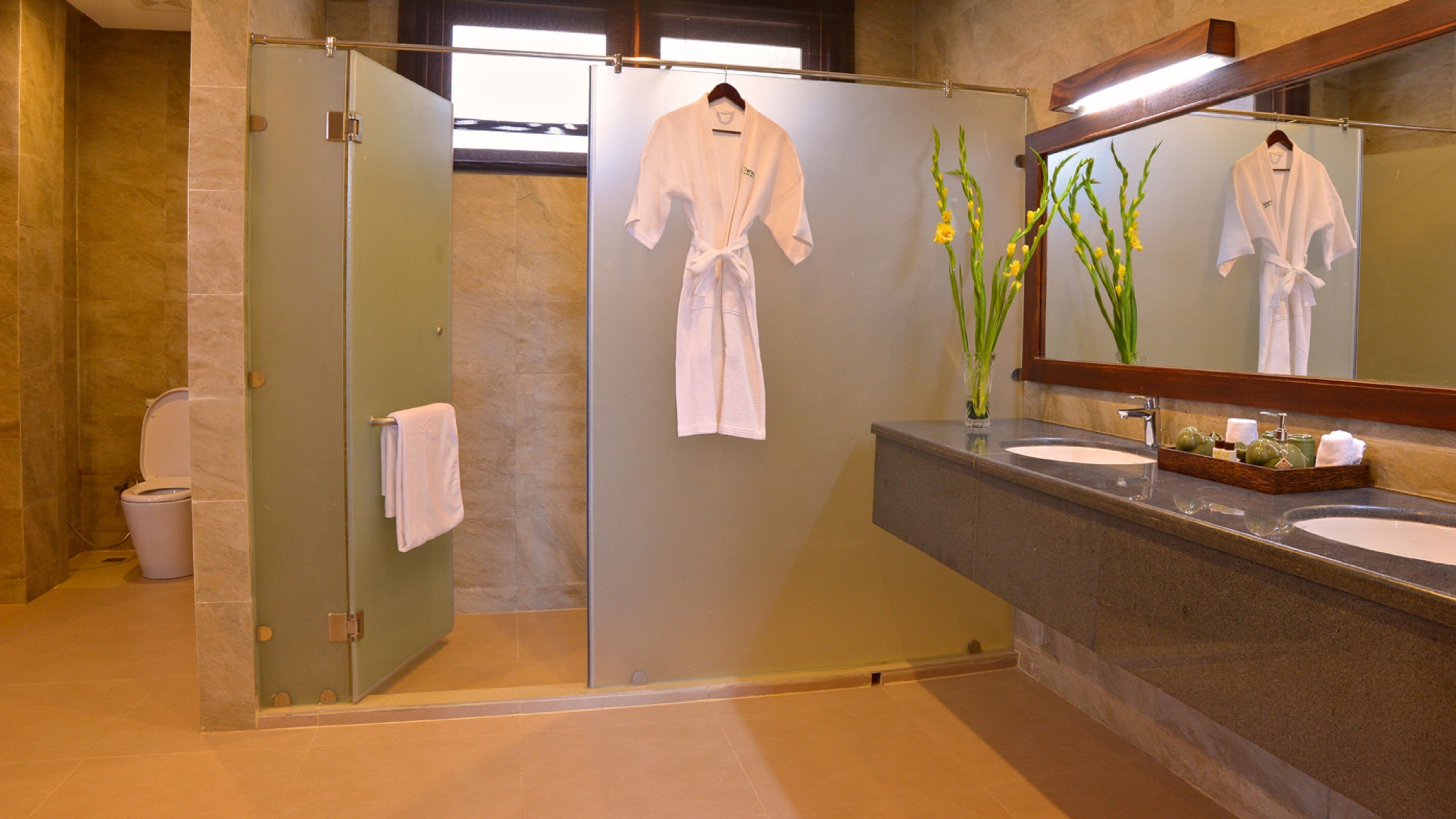 A bathroom with a glass partition, a sink, a mirror, and a towel rack.