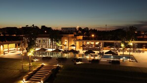 A hotel with a swimming pool, outdoor seating, and a well-lit entrance area. - Emerald Palace Hotel (Naypyidaw)