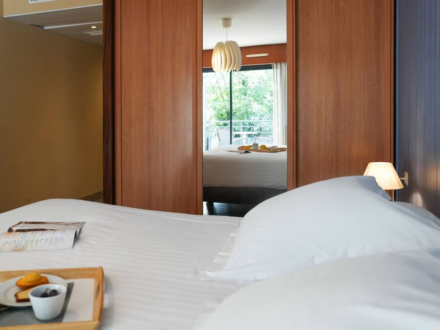 Een hotelkamer met een bed, een dienblad met ontbijtartikelen, een raam met uitzicht en een lamp.