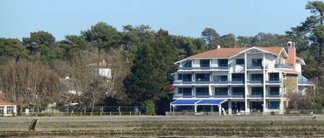 A multi-story hotel with balconies, located near a body of water.