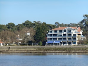 Un hotel de varios pisos con balcones, situado cerca del agua.
