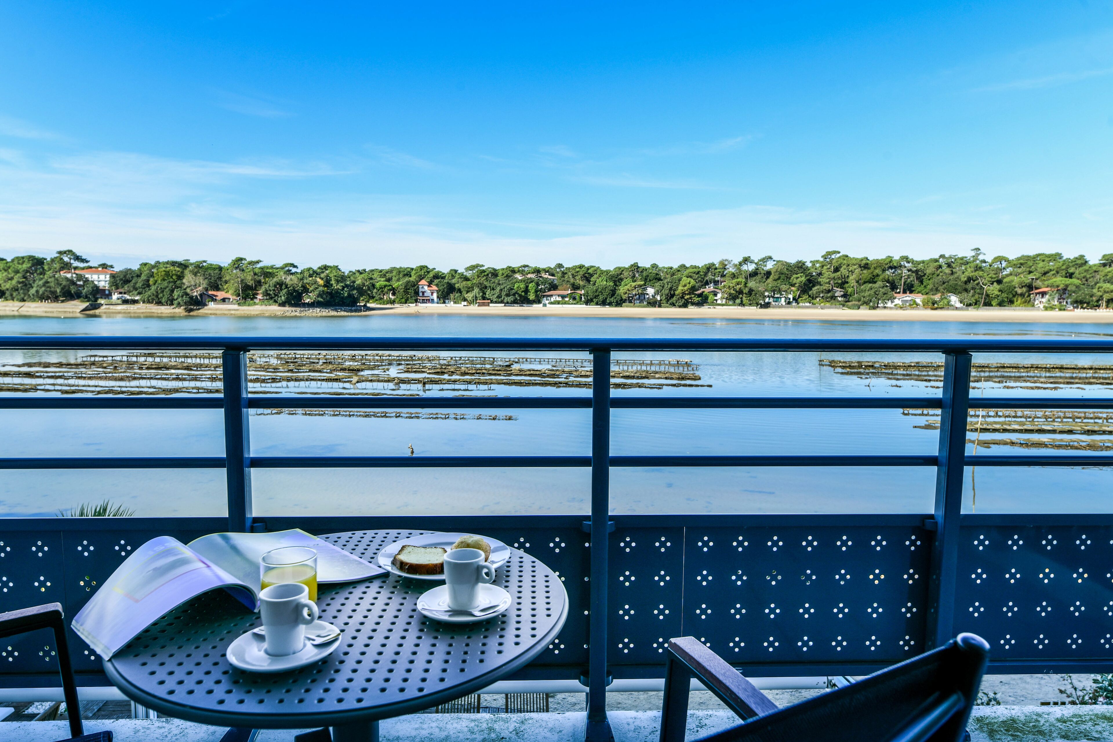 Una mesa con vistas a un lago y una playa, un libro y una taza de café.