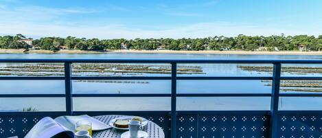 Una mesa con vistas a un lago y una playa, un libro y una taza de café.