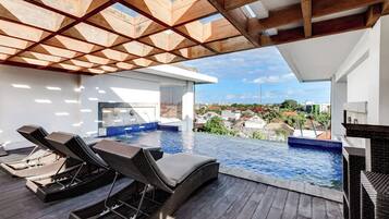 A rooftop infinity pool with lounge chairs and a view of the city.