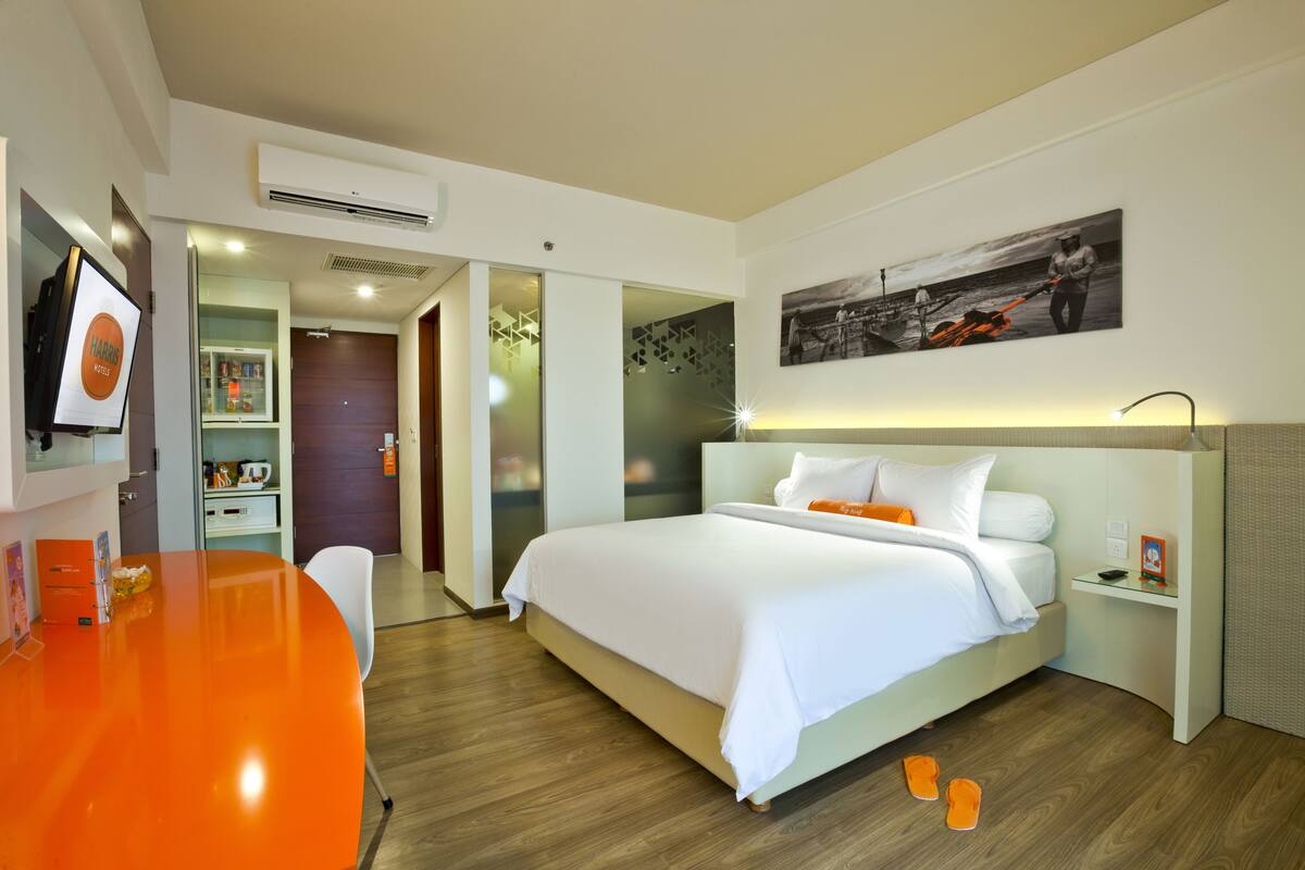 A modern hotel room with a large bed, a desk with a computer, and a television.