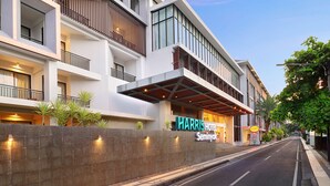 A modern hotel with a prominent sign, multiple balconies, and a stone wall with lights. - HARRIS Hotel Seminyak Bali (Seminyak)