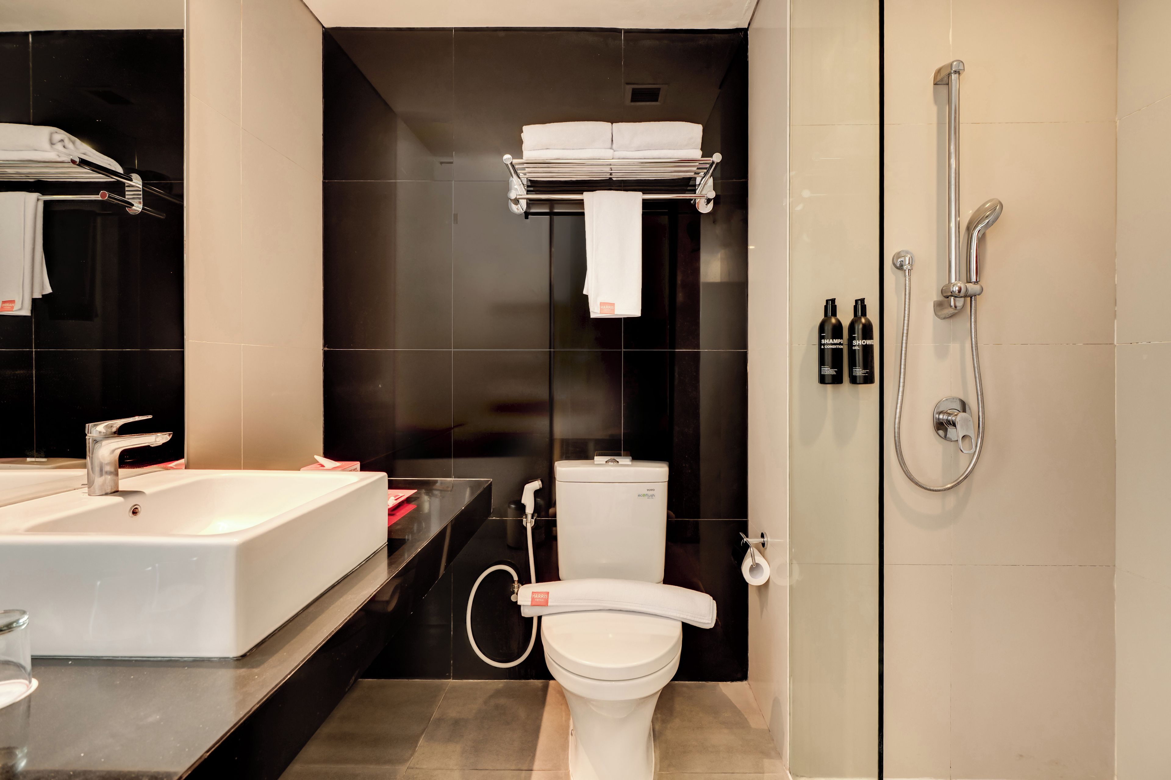A modern bathroom with a large white sink, a toilet, and a shower.