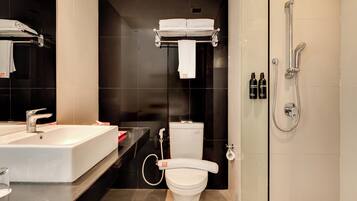 A modern bathroom with a large white sink, a toilet, and a shower.