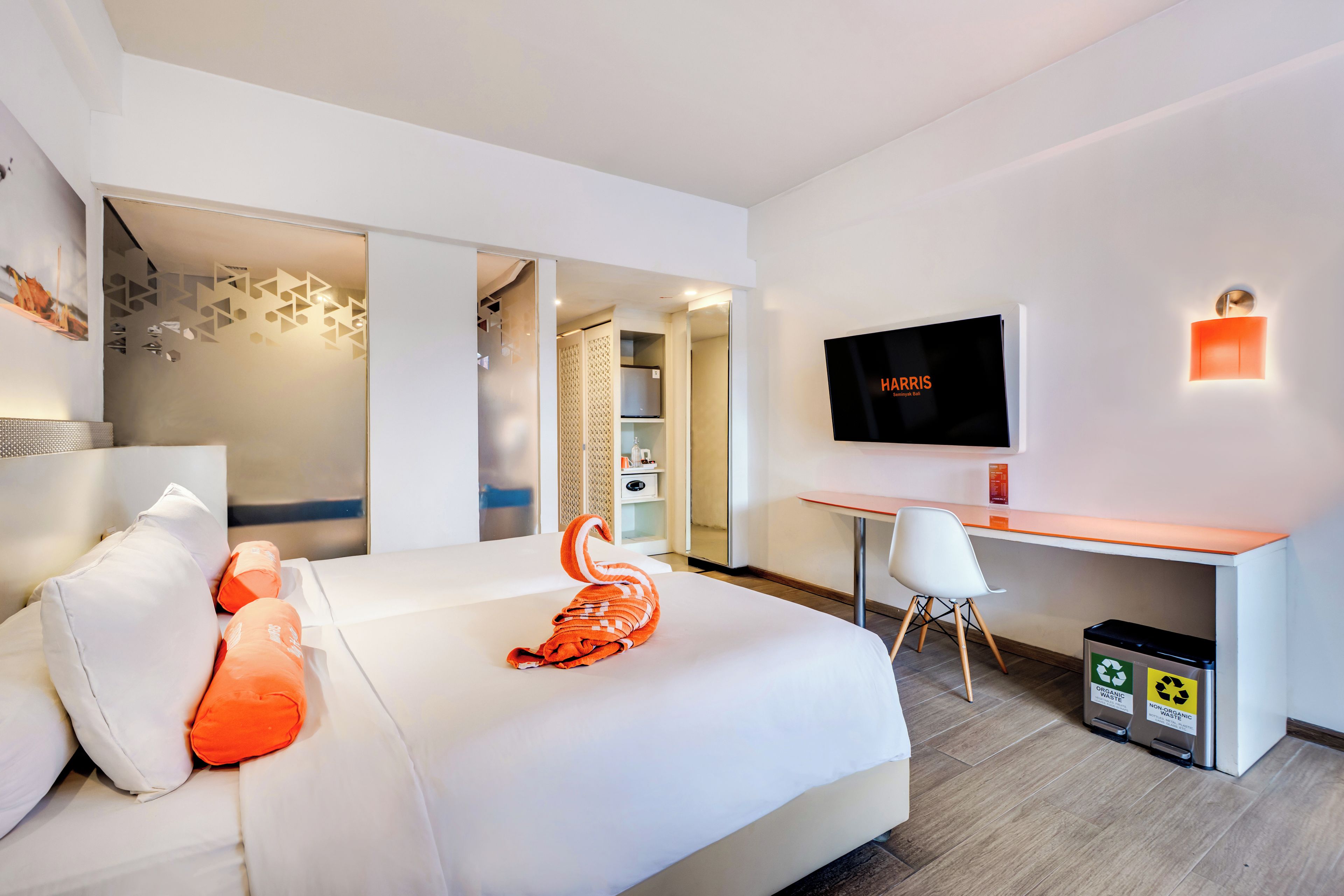 Una habitación de hotel moderna con cama, escritorio, televisor y un cesto de basura.
