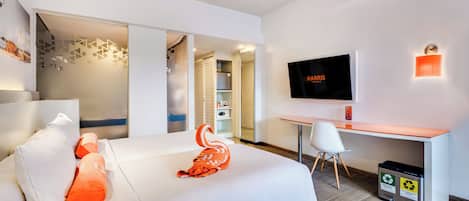 Una habitación de hotel moderna con cama, escritorio, televisor y un cesto de basura.