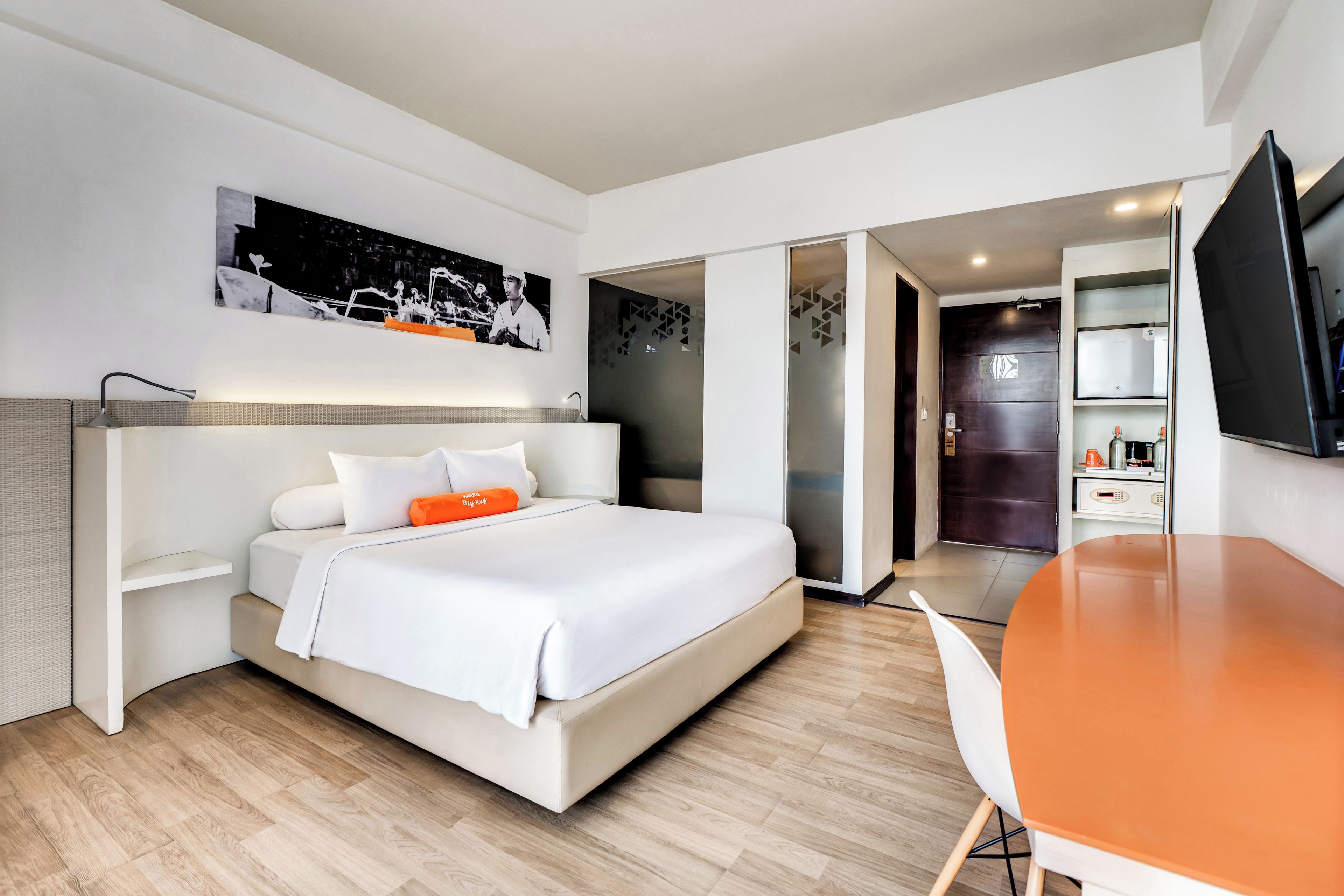 A modern hotel room with a bed, a desk, and a television.