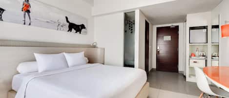 A hotel room with a bed, a desk, a chair, and a painting on the wall.
