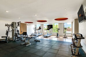 Une salle de sport équipée de divers appareils d’exercice, notamment des tapis de course et des appareils de musculation.