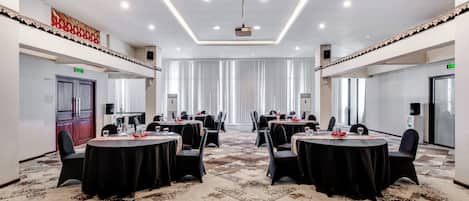 A conference room with round tables, black chairs, and a patterned carpet.