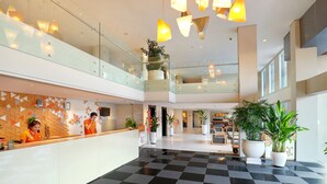 A modern hotel lobby with a checkered floor, glass railings, and potted plants. - HARRIS Hotel Seminyak Bali (Seminyak)