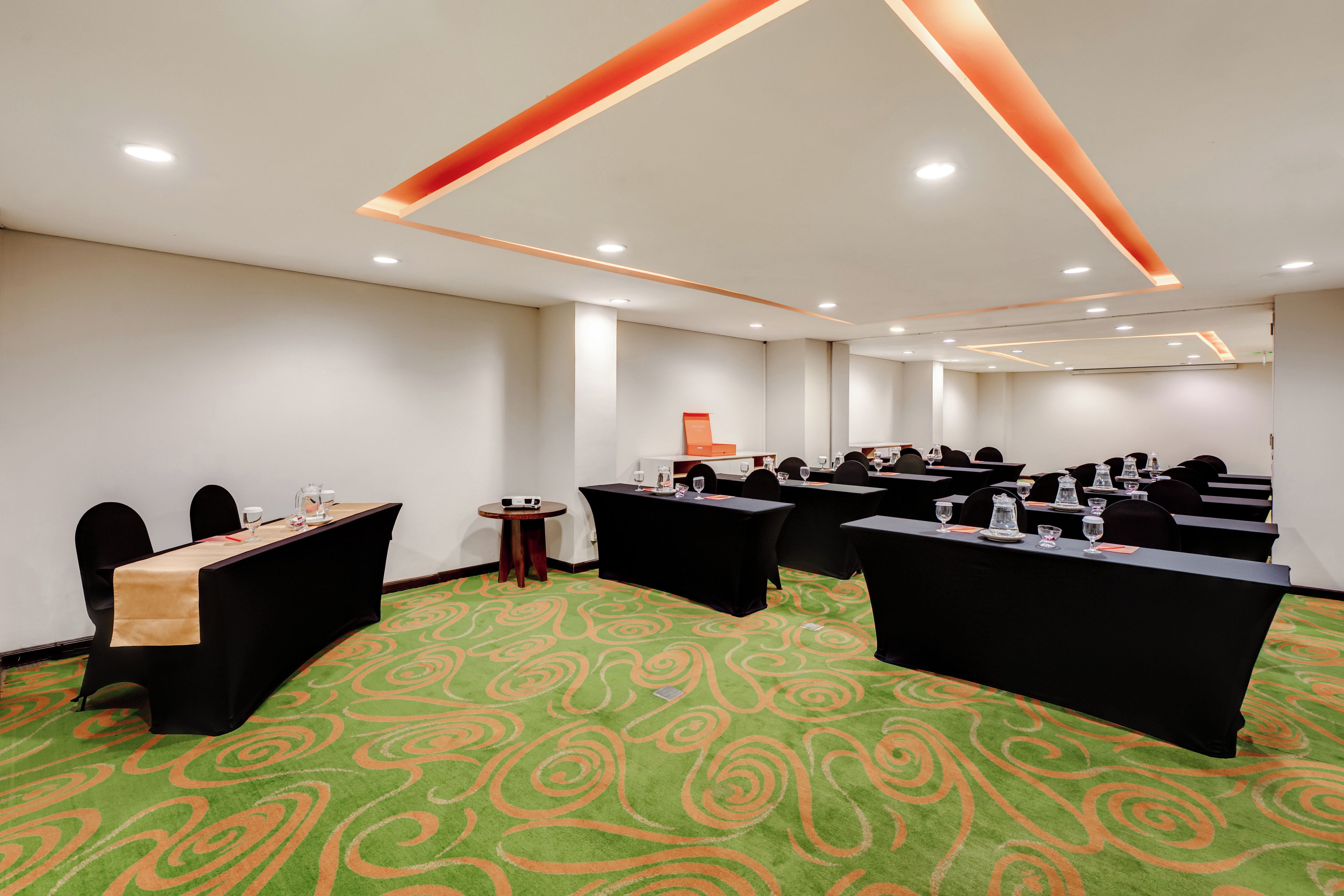 A conference room with multiple tables, chairs, and a carpeted floor.