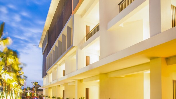 A modern hotel with a pool, multiple balconies, and a well-lit exterior. - HARRIS Hotel Seminyak Bali (Seminyak)