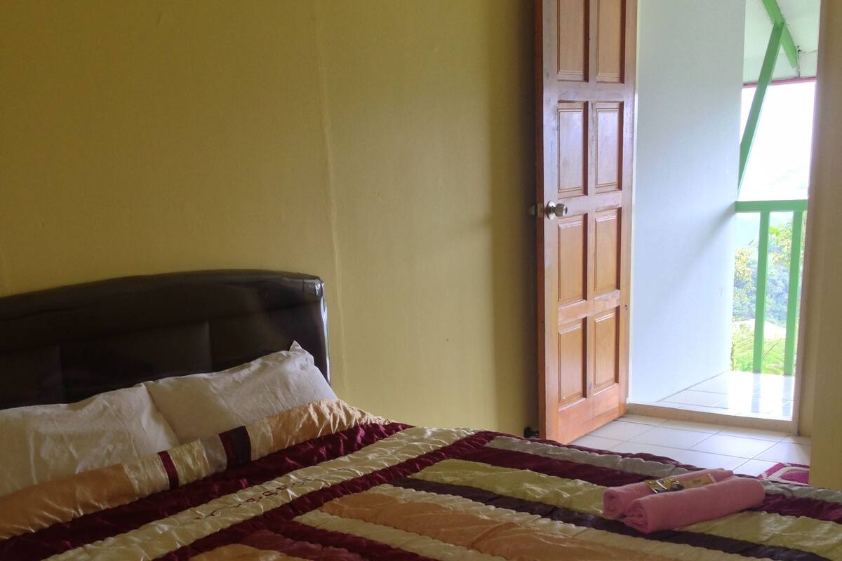 Ein Bett mit einer gestreiften Bettdecke in einem Zimmer mit gelben Wänden und einer Holztür.