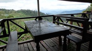 A wooden deck with a table and benches overlooking a mountainous landscape.