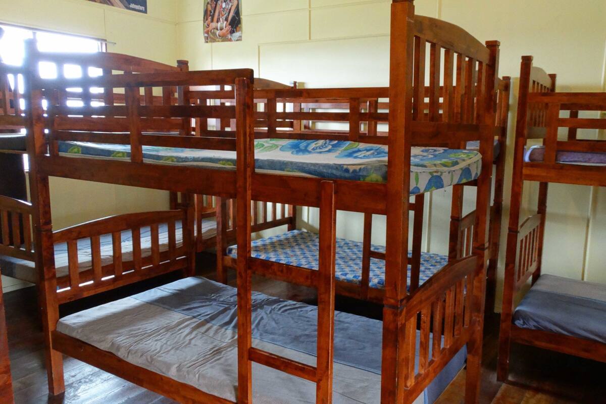 Ein Schlafzimmer mit Etagenbetten, Holzrahmen und blau gemusterten Betttextilien.