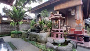 Un patio tradicional con senderos de piedra, una fuente decorativa y un santuario.