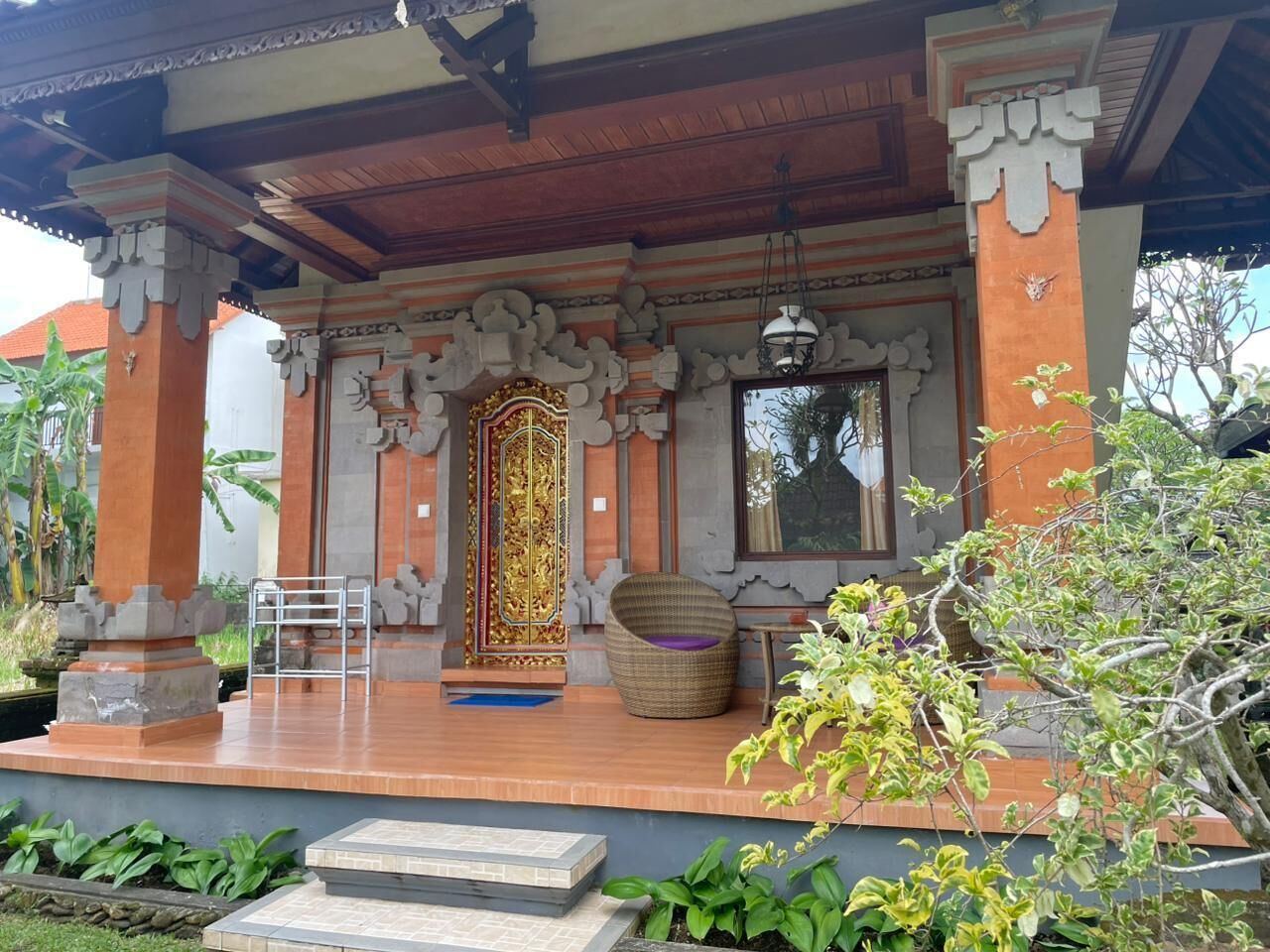 Un edificio tradicional con un porche cubierto, una entrada decorativa y una zona de estar con una silla y una mesa.