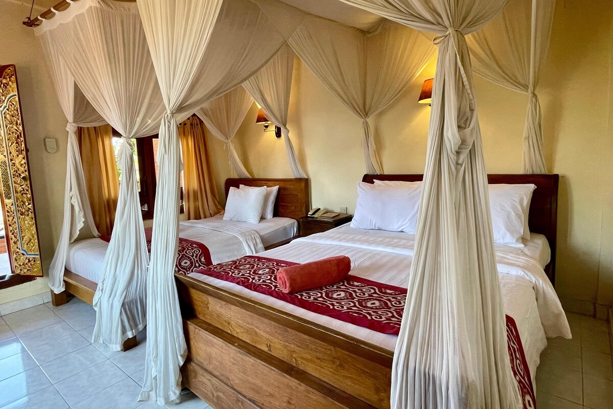 A four-poster canopy bed with a wooden headboard, white bedding, and a red patterned throw.