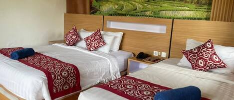 Une chambre d’hôtel avec trois lits, chacun agrémenté d’une couvre-lit et de coussins à motifs, d’une tête de lit en bois et d’un grand tableau représentant un paysage, placé au-dessus des lits.