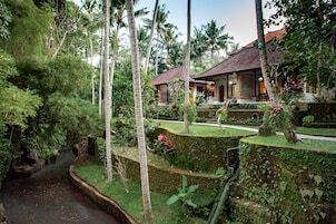 A tropical resort with a water channel, lush greenery, and traditional-style buildings with tiled roofs.