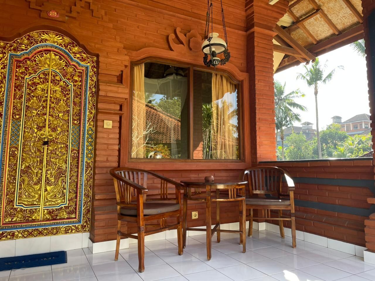 A room with a wooden table and chairs, a large window with curtains, and a decorative wall panel.