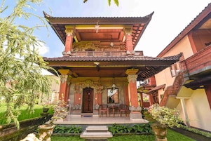 A traditional building with a multi-tiered roof, a central staircase, and a small outdoor seating area with chairs and a table.