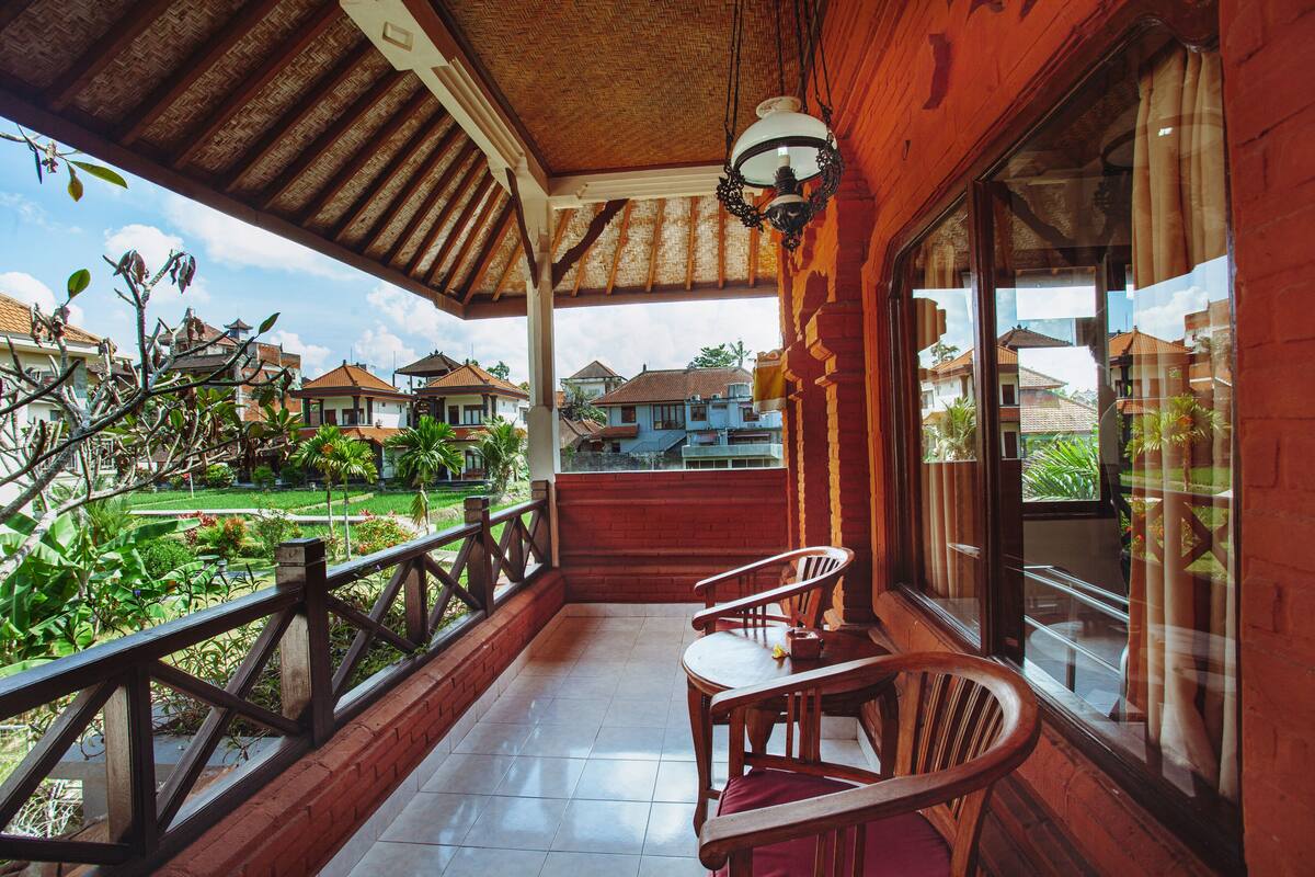 A wooden veranda with a tiled floor, a wooden railing, and a table with chairs.