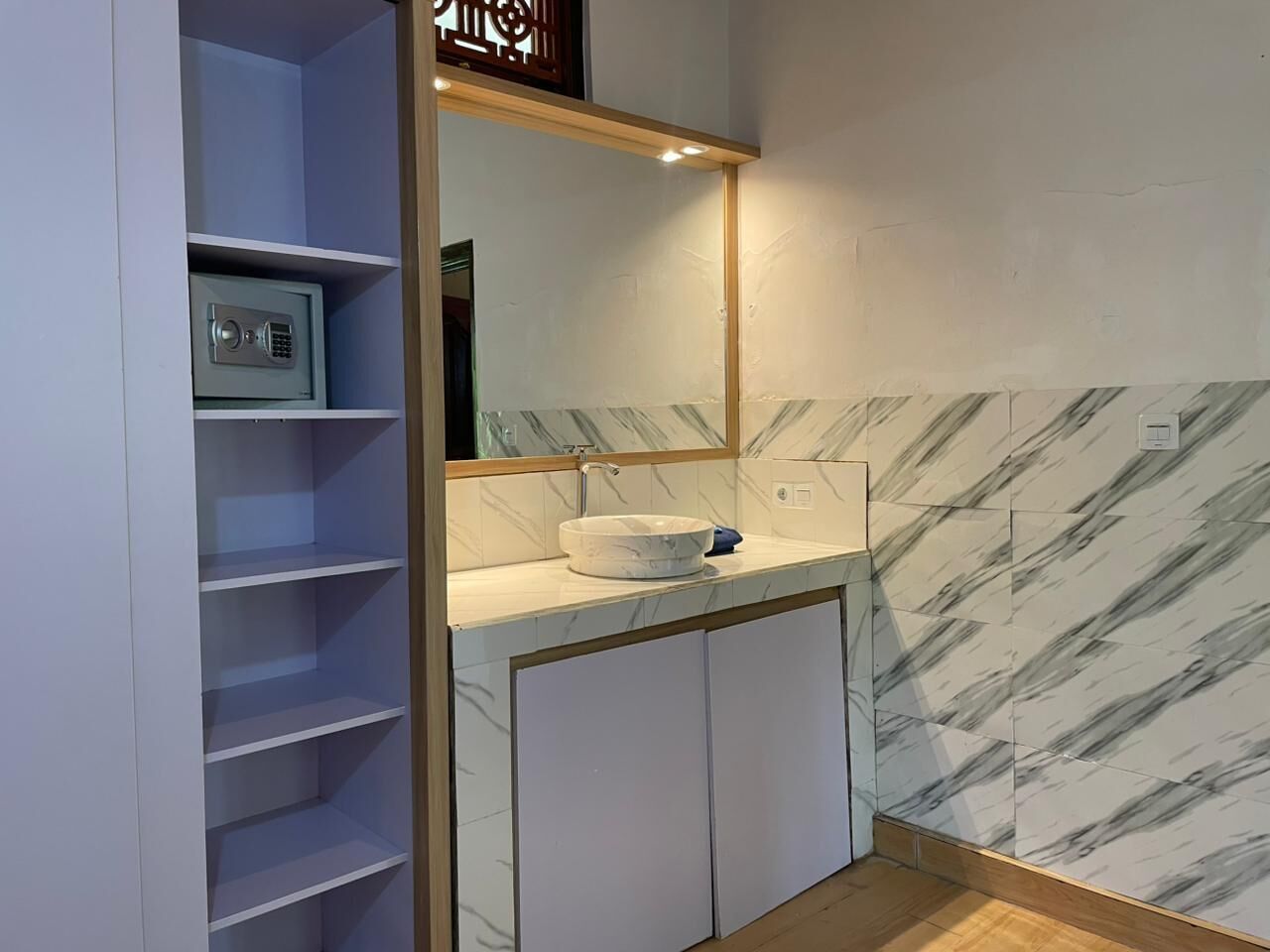 A bathroom with a marble backsplash, a sink, and a mirror above it.