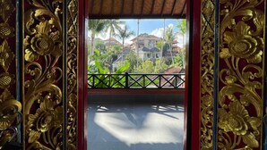 A balcony with ornate golden railings and a view of a residential area with palm trees and houses. - Nick's Pension (Ubud)