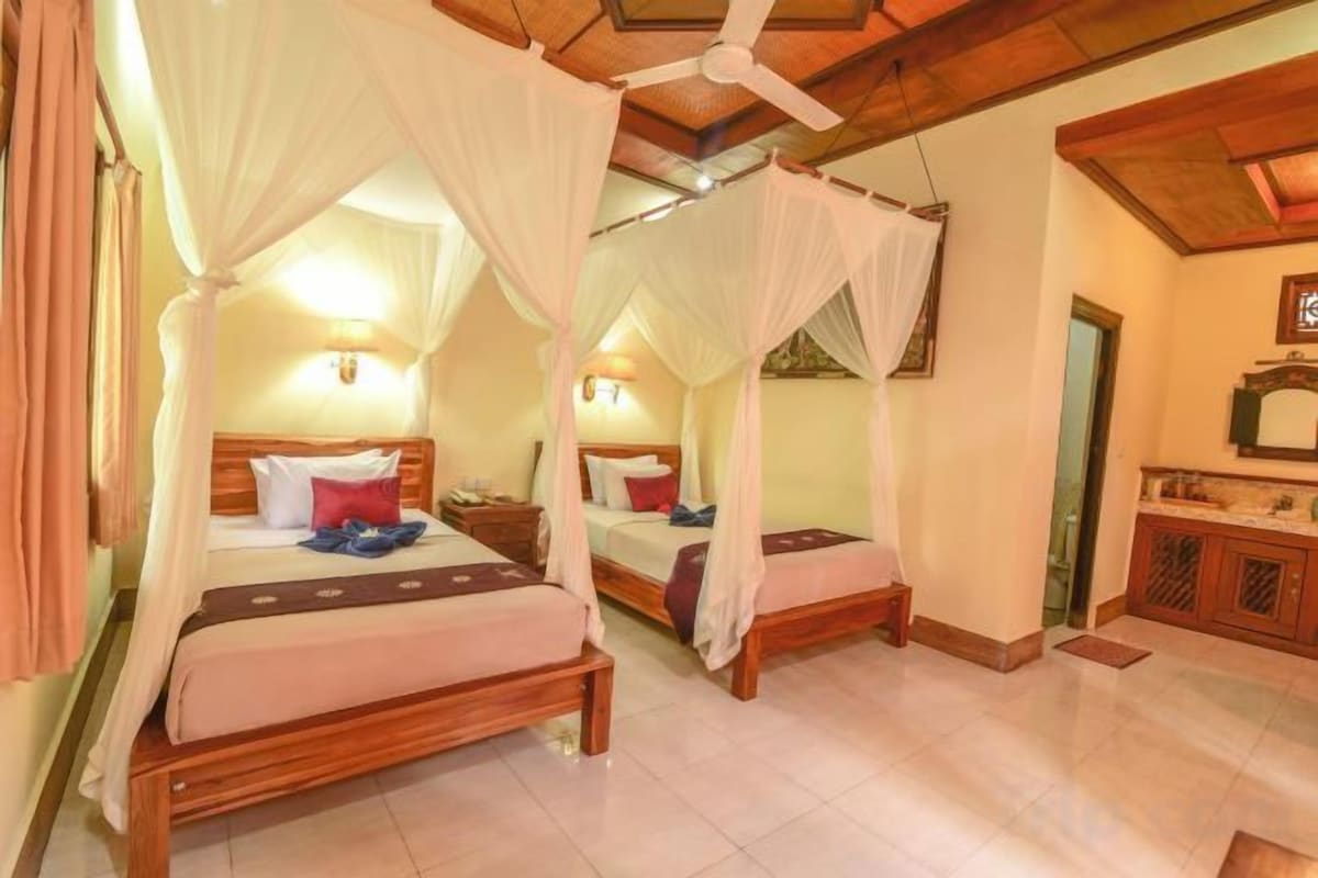 A room with two beds, each with a canopy, wooden headboards, and bedside tables.