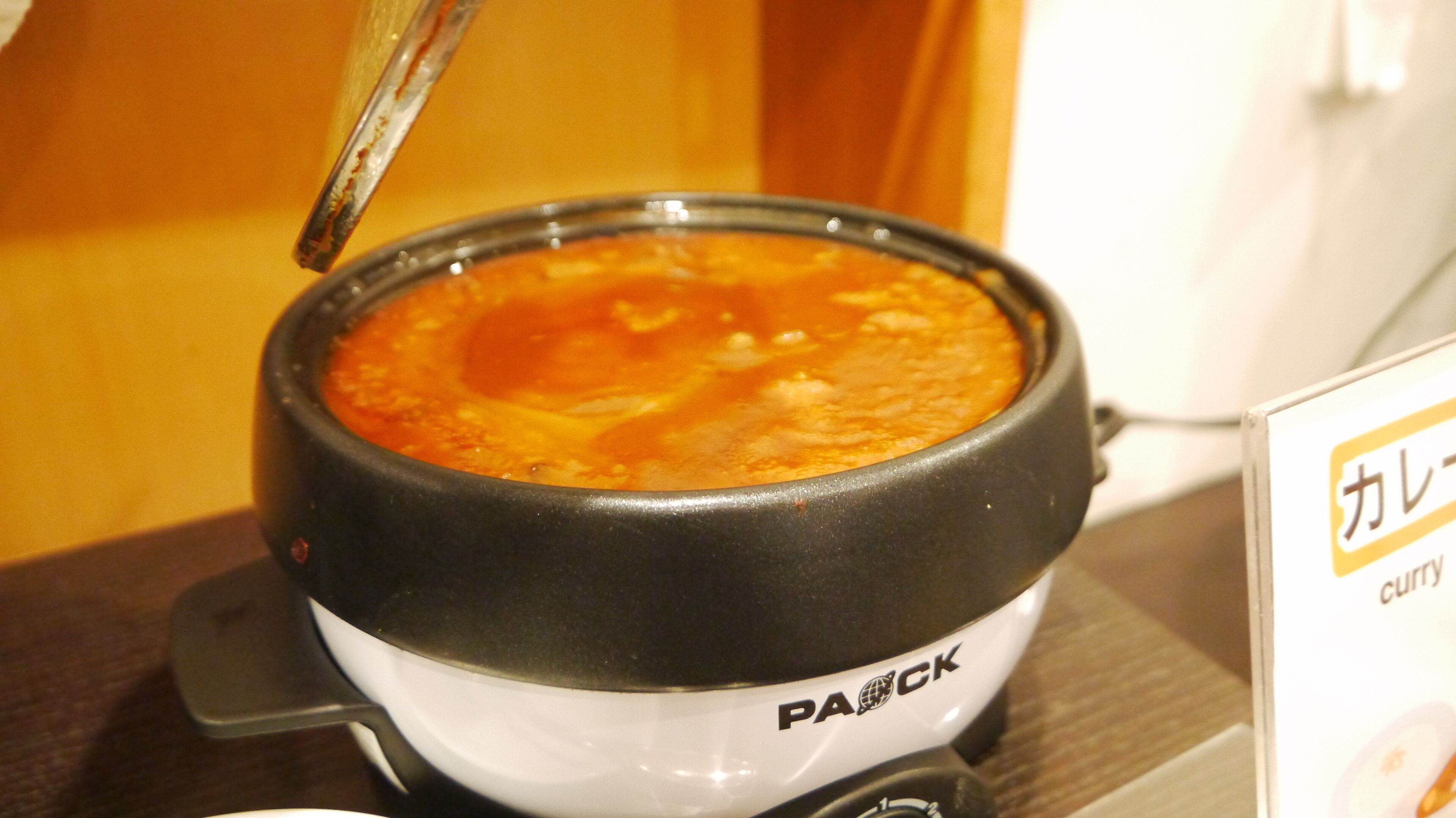 Une poêle électrique de la marque PAANICK, avec un couvercle, posée sur une cuisinière.