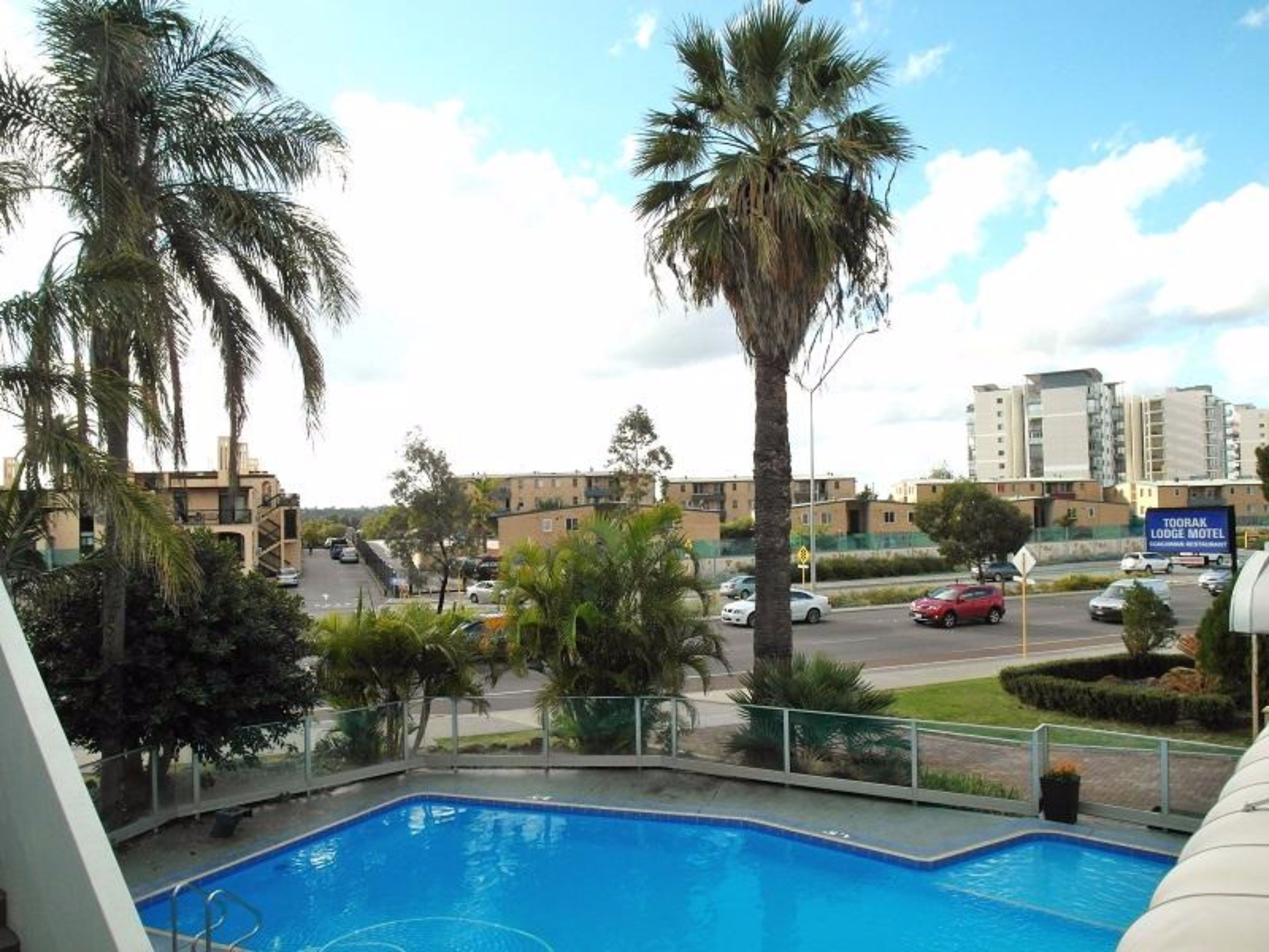 Zona de piscina con vista a una carretera y edificios al fondo.