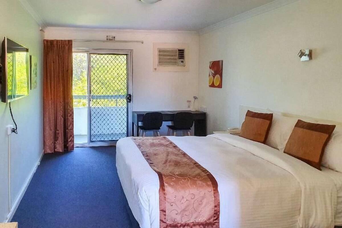 A hotel room with a bed, a desk, and a chair.
