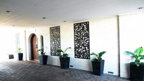 A hallway with a brick floor, white walls, and black decorative panels.