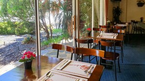 A restaurant with tables set for dining, featuring a view of the outdoors.