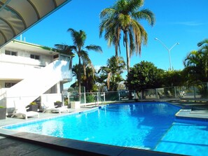A swimming pool with palm trees and a building in the background.