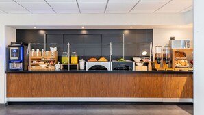 A modern breakfast bar with a coffee machine, juice dispensers, and a variety of food items.