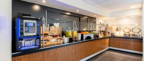 Una cocina moderna con una cafetera KREA, armarios de madera y una vitrina de vidrio con productos alimenticios.