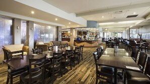 A spacious hotel dining area with multiple tables and chairs, a bar, and large windows providing natural light. - Nightcap at Morwell Hotel (Morwell)