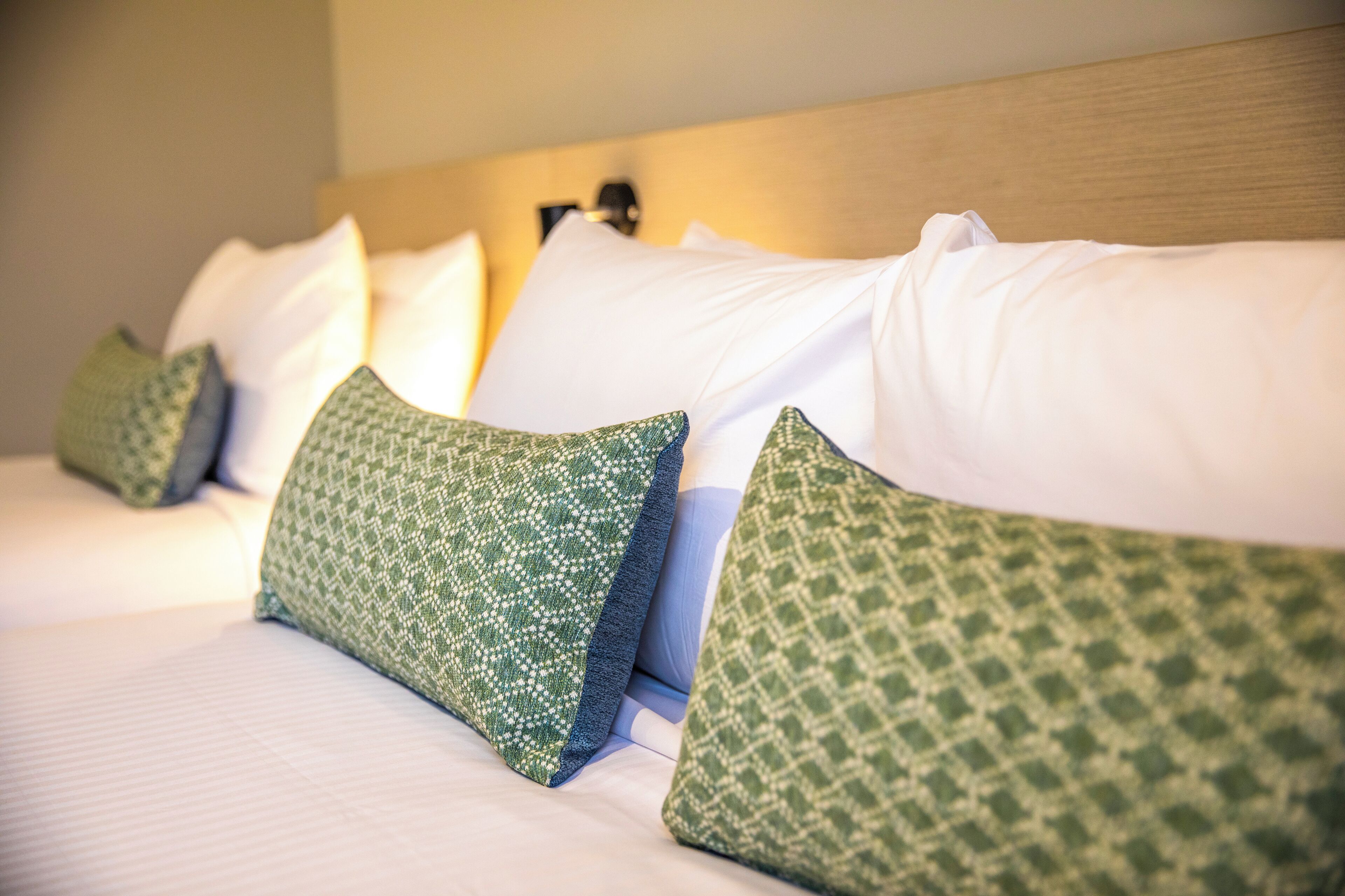 A neatly made bed with white and green patterned pillows.