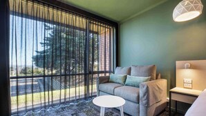 A room with a sofa, a small round table, a lamp, and a view through a window with blinds. - Nightcap at Morwell Hotel (Morwell)