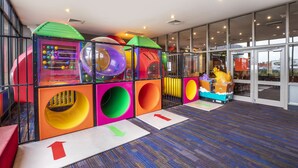 A children's play area with colorful play structures and a large glass entrance.