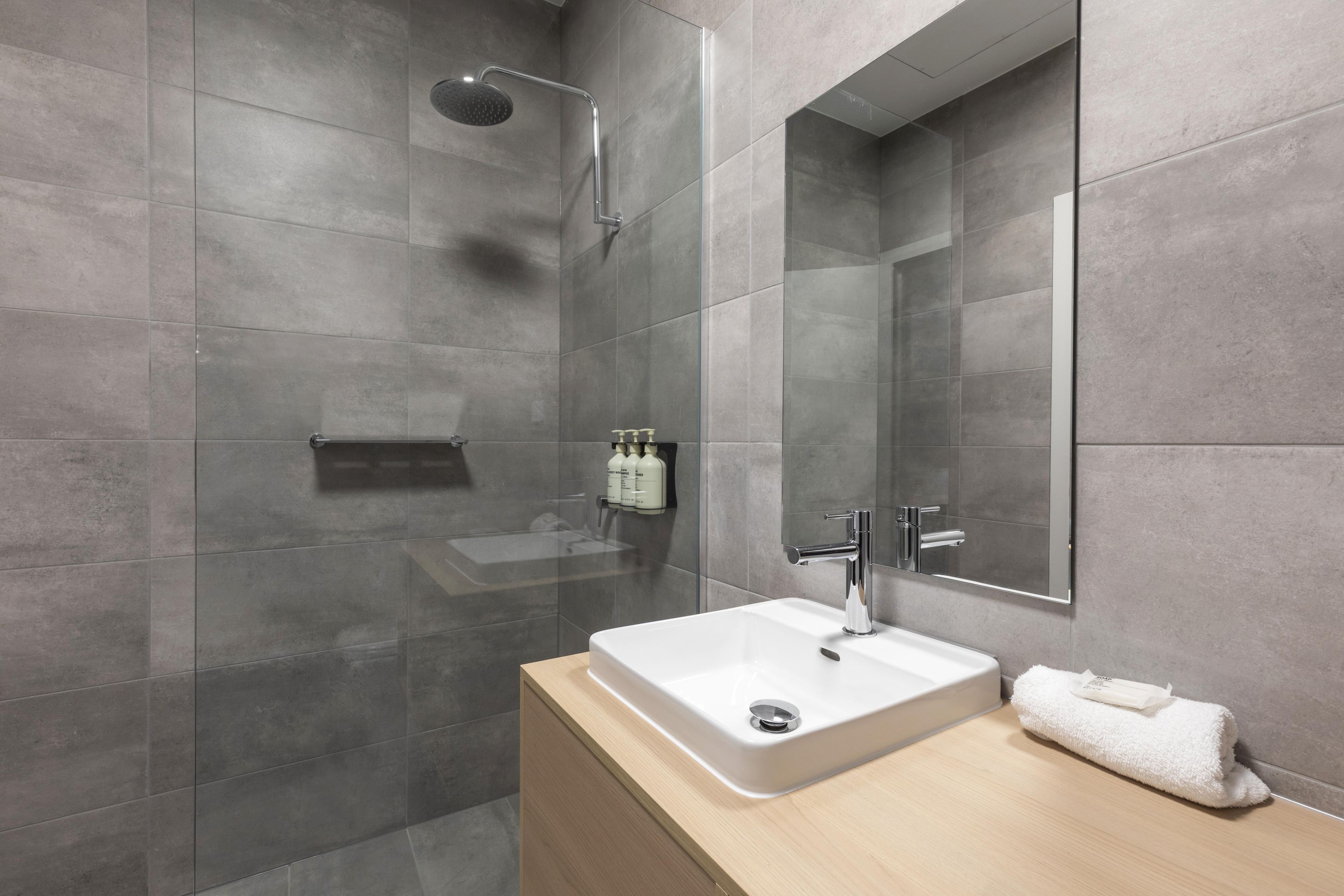 A modern bathroom with a glass-enclosed shower, a white sink, and a mirror above it.