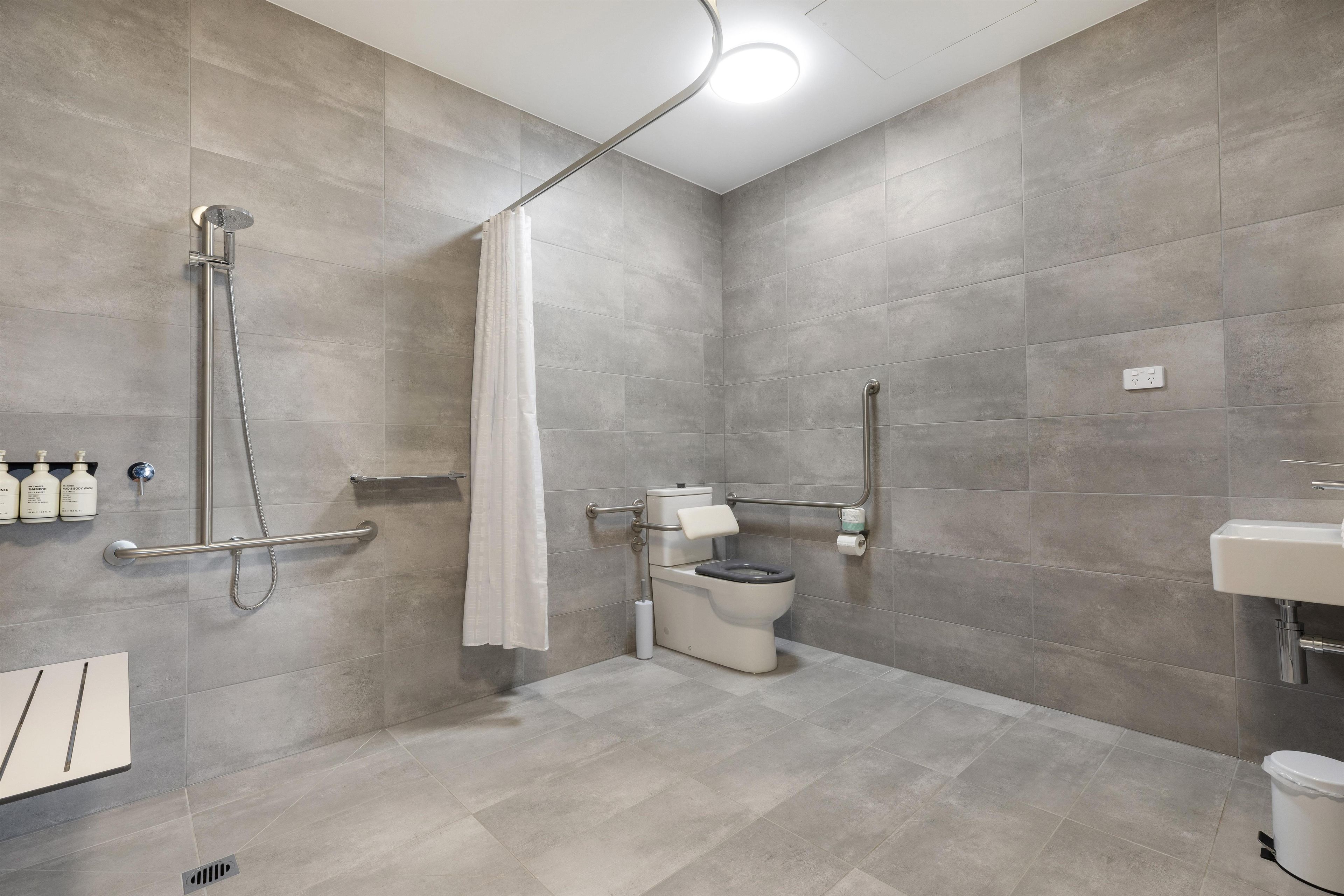 Et moderne badeværelse med bruser, toilet og håndvask.